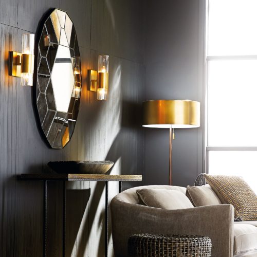 elegant antiqued oval wall mirror flanked by two Hollywood regancy wall sconce. Modern living room with elegant gold accents warm up the gray walls.
